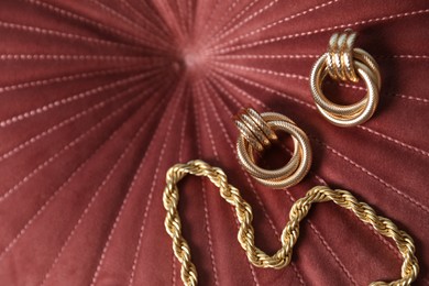 Photo of Beautiful gold jewelry on velvet fabric, above view. Space for text