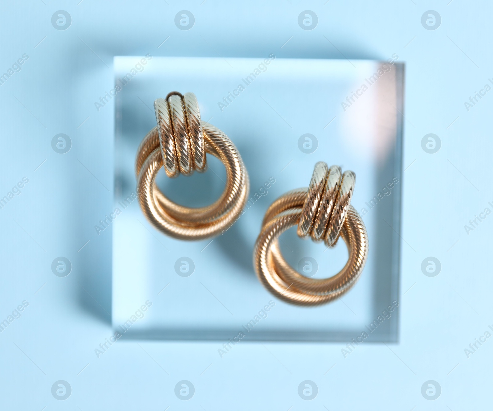 Photo of Beautiful gold earrings on light blue background, top view