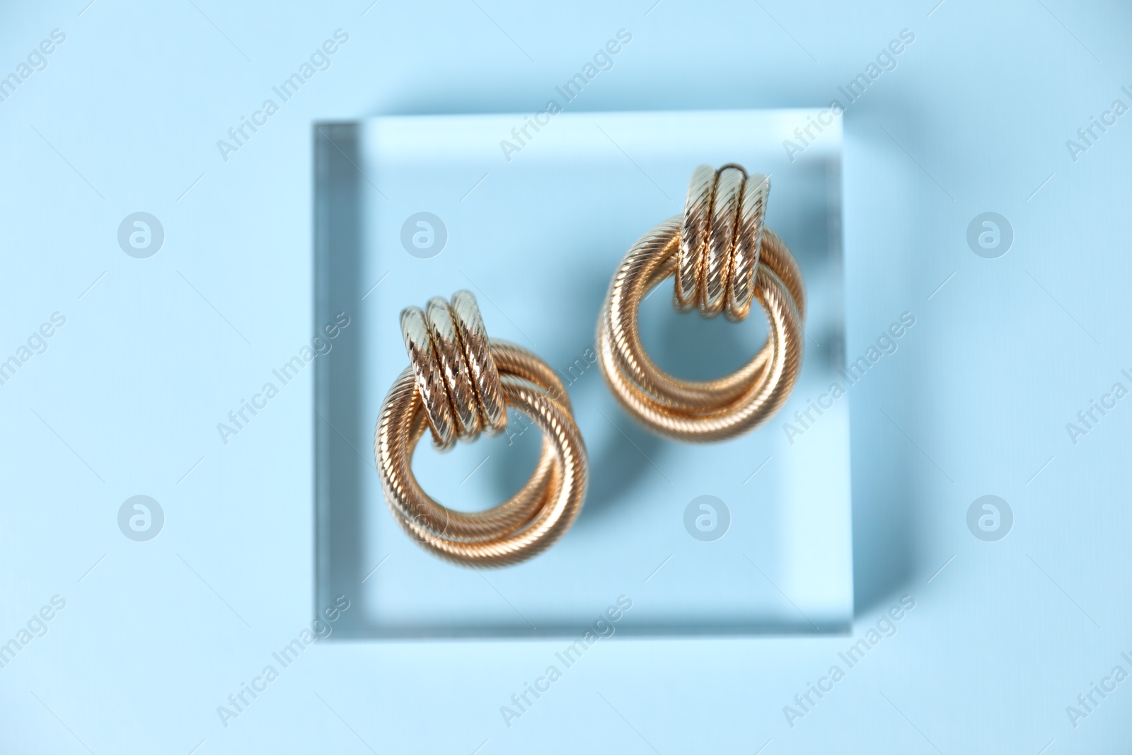 Photo of Beautiful gold earrings on light blue background, top view
