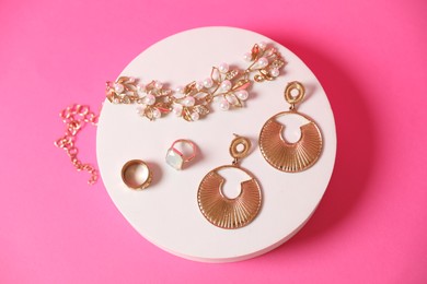 Photo of Stylish presentation of beautiful gold jewelry on pink background, top view