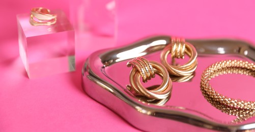 Photo of Stylish presentation of beautiful gold jewelry on pink background, closeup