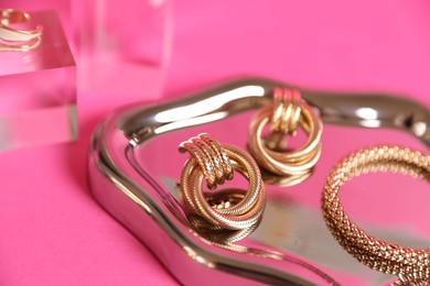 Photo of Stylish presentation of beautiful gold jewelry on pink background, closeup
