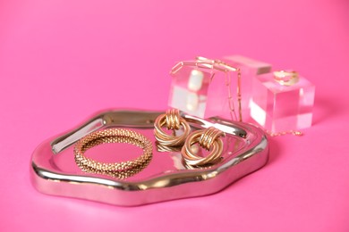 Photo of Stylish presentation of beautiful gold jewelry on pink background, closeup