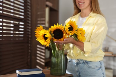 Photo of Woman with beautiful sunflowers at home, closeup. Space for text
