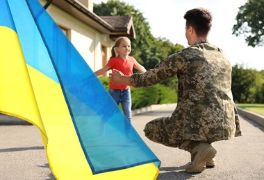 Image of Military man and his happy daughter outdoors. Double exposure with flag of Ukraine