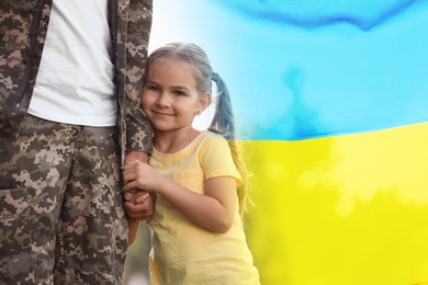 Image of Military man and his happy daughter outdoors. Double exposure with flag of Ukraine
