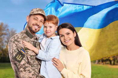 Image of Happy military man with his family and flag of Ukraine outdoors