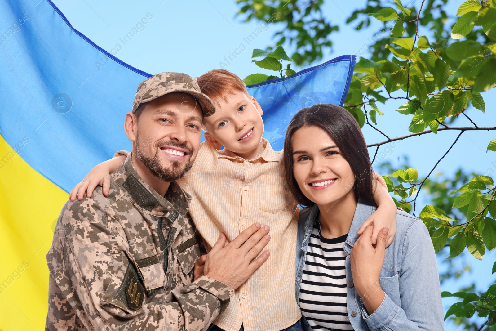 Image of Happy military man with his family and flag of Ukraine outdoors