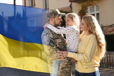 Image of Happy military man and his family outdoors. Double exposure with flag of Ukraine