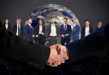 Image of Business partners shaking hands against group of people. Globe on background