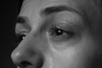 Photo of Sad woman crying on dark background, closeup. Black and white effect