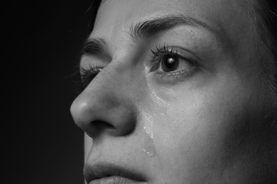 Photo of Sad woman crying on dark background, closeup. Black and white effect