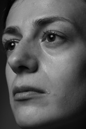 Photo of Sad woman crying on dark background, closeup. Black and white effect
