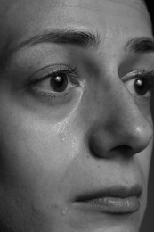 Photo of Sad woman crying on dark background, closeup. Black and white effect