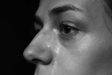 Photo of Sad woman crying on dark background, closeup. Black and white effect