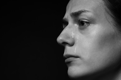 Photo of Sad woman crying on dark background, closeup. Black and white effect
