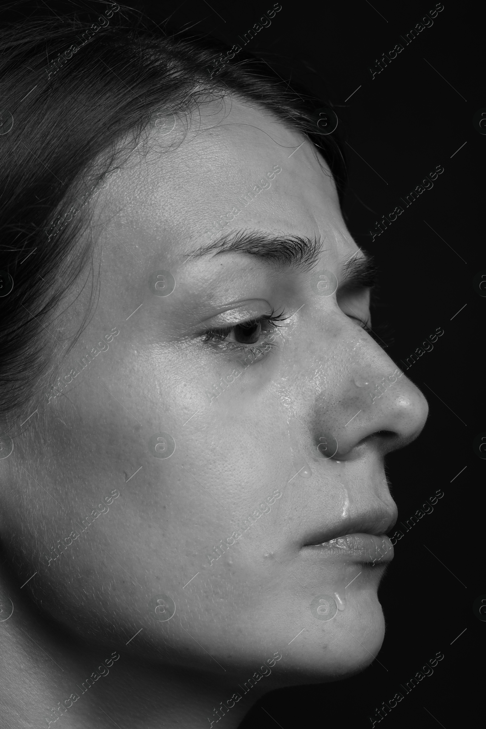 Photo of Sad woman crying on dark background, closeup. Black and white effect