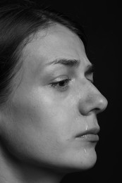 Photo of Sad woman crying on dark background, closeup. Black and white effect