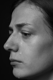 Photo of Sad woman crying on dark background, closeup. Black and white effect