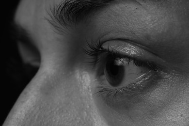 Photo of Sad woman crying on dark background, closeup. Black and white effect