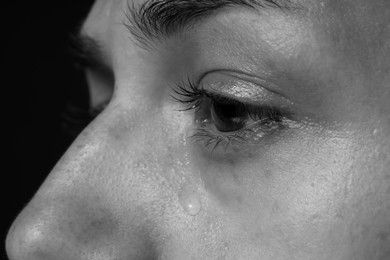 Photo of Sad woman crying on dark background, closeup. Black and white effect