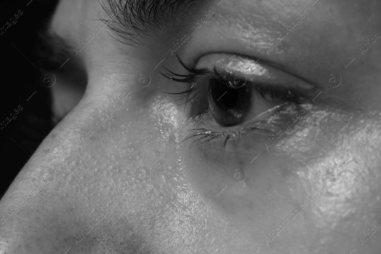 Photo of Sad woman crying on dark background, closeup. Black and white effect