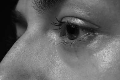 Photo of Sad woman crying on dark background, closeup. Black and white effect