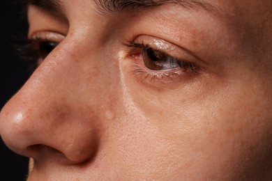 Photo of Sad woman crying on black background, closeup