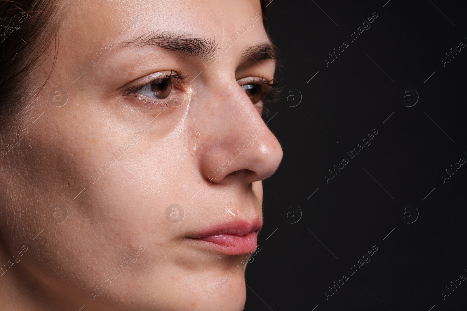 Photo of Sad woman crying on black background, closeup. Space for text