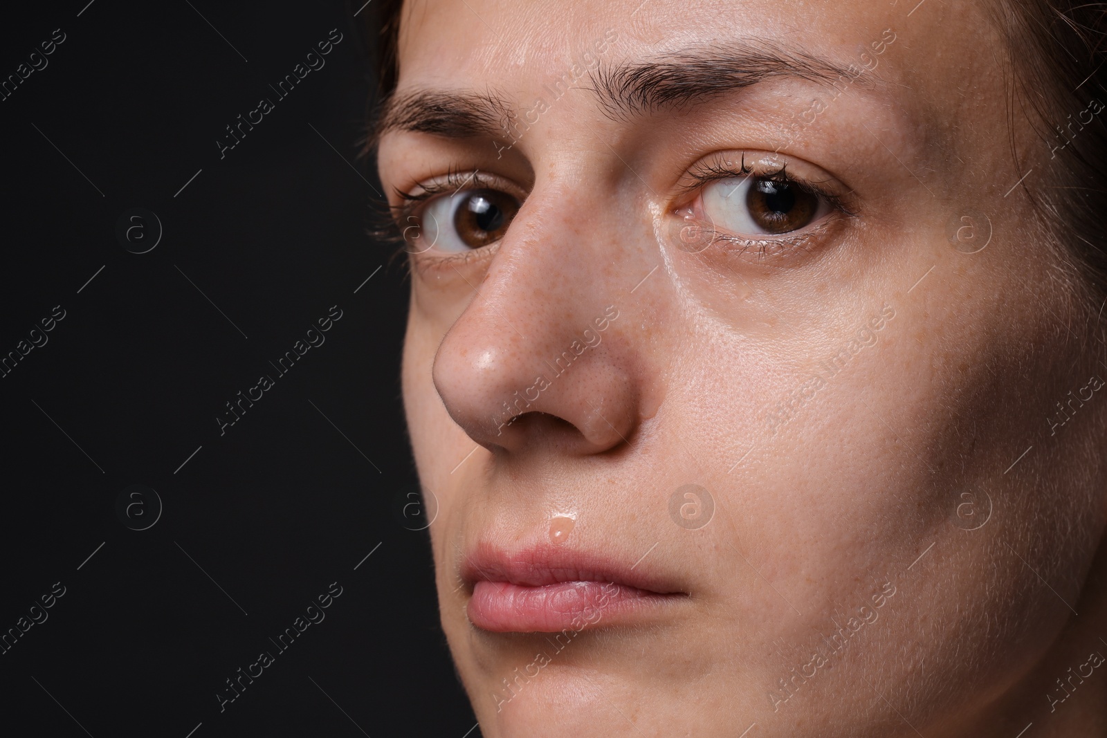 Photo of Sad woman crying on black background, closeup. Space for text