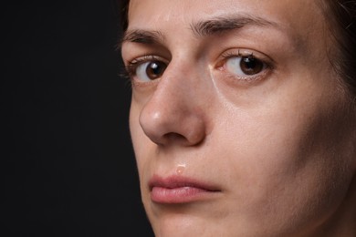Photo of Sad woman crying on black background, closeup. Space for text