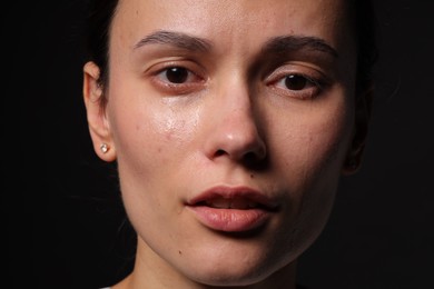Photo of Sad woman crying on black background, closeup