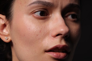 Photo of Sad woman crying on black background, closeup