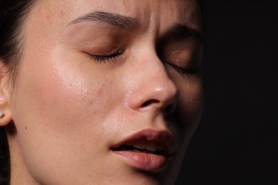 Photo of Sad woman crying on black background, closeup. Space for text