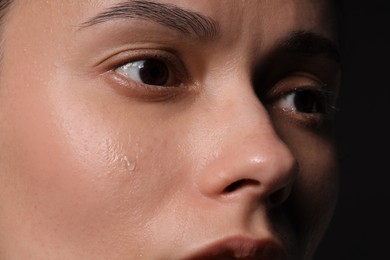 Photo of Sad woman crying on black background, closeup