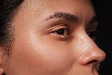 Photo of Sad woman crying on black background, closeup