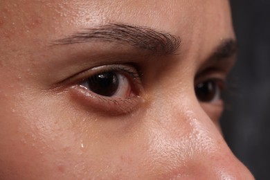 Photo of Sad woman crying on dark background, closeup