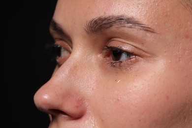 Photo of Sad woman crying on black background, closeup