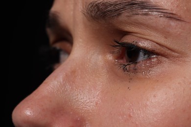 Photo of Sad woman crying on black background, closeup