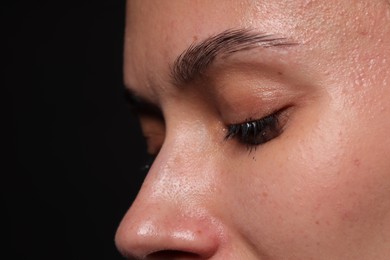 Photo of Sad woman crying on black background, closeup. Space for text