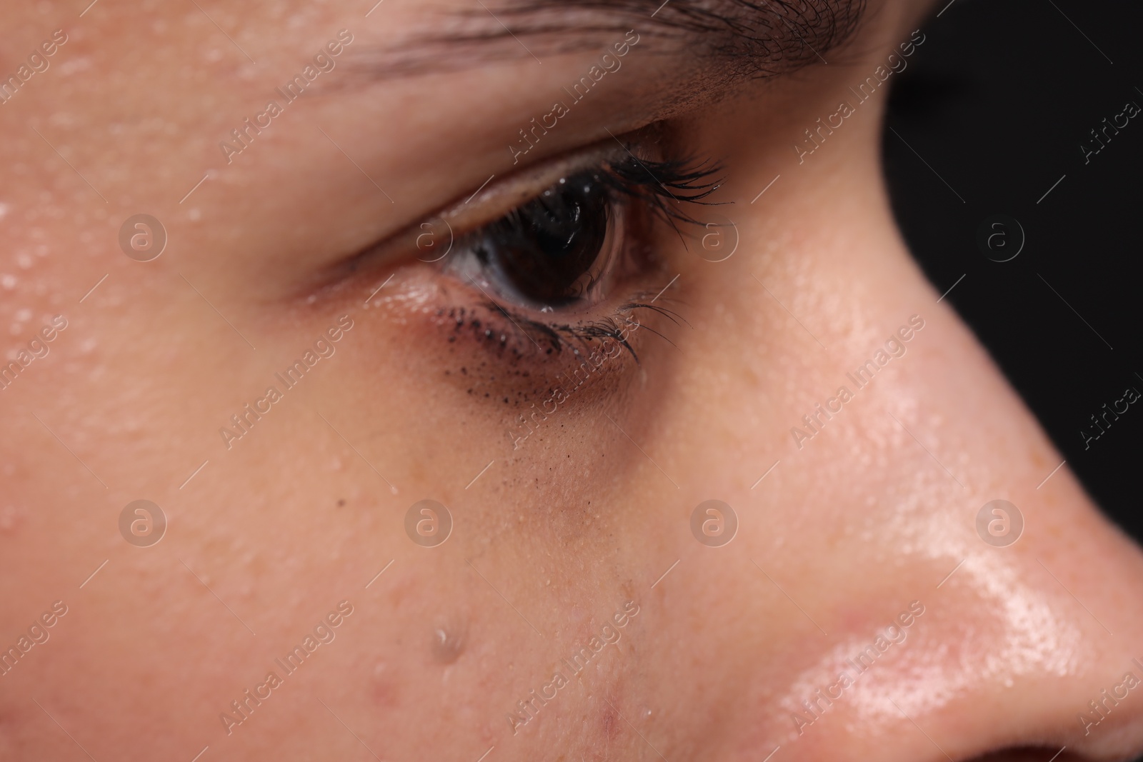 Photo of Sad woman crying on black background, closeup