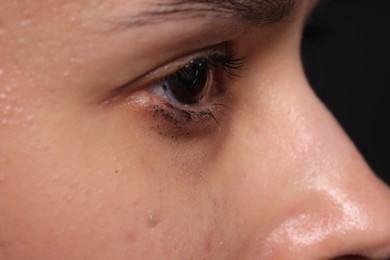 Photo of Sad woman crying on black background, closeup