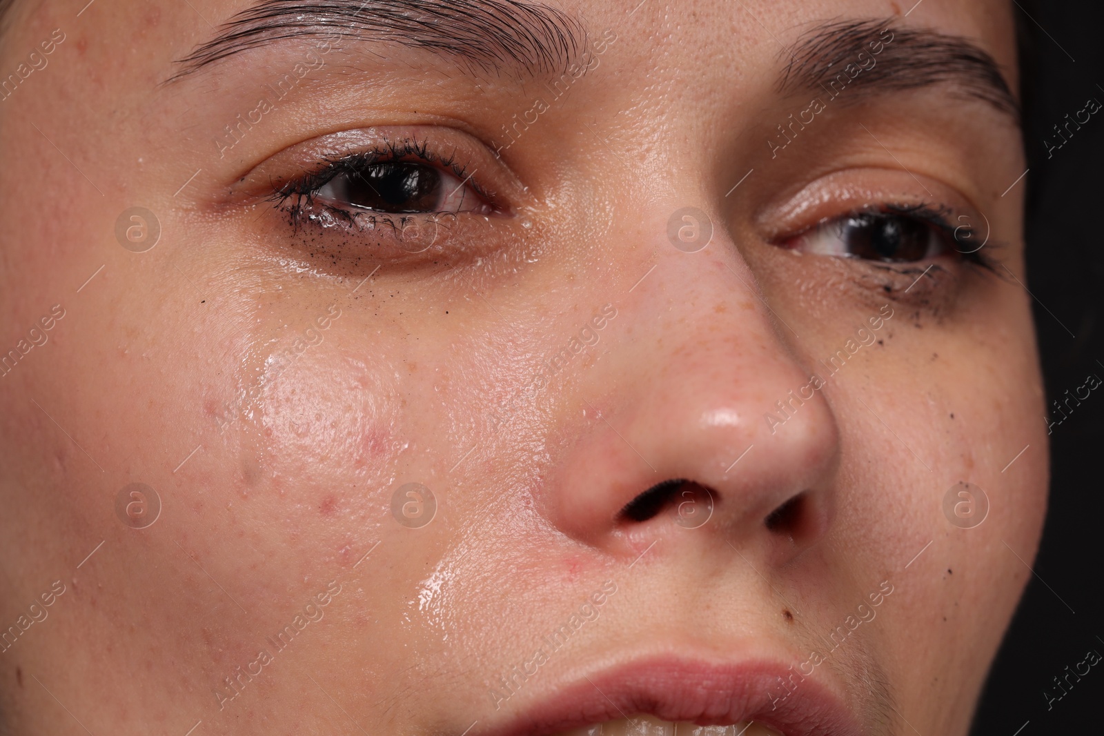 Photo of Sad woman crying on black background, closeup