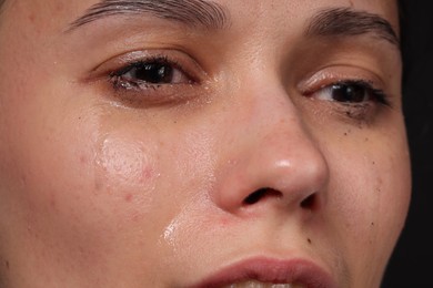Photo of Sad woman crying on black background, closeup
