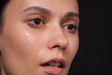 Photo of Sad woman crying on black background, closeup. Space for text