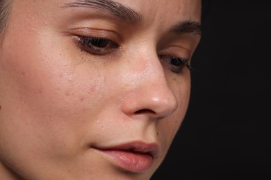 Photo of Sad woman crying on black background, closeup. Space for text