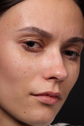 Photo of Sad woman crying on black background, closeup