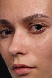 Photo of Sad woman crying on black background, closeup