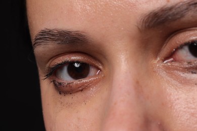 Photo of Sad woman crying on black background, closeup