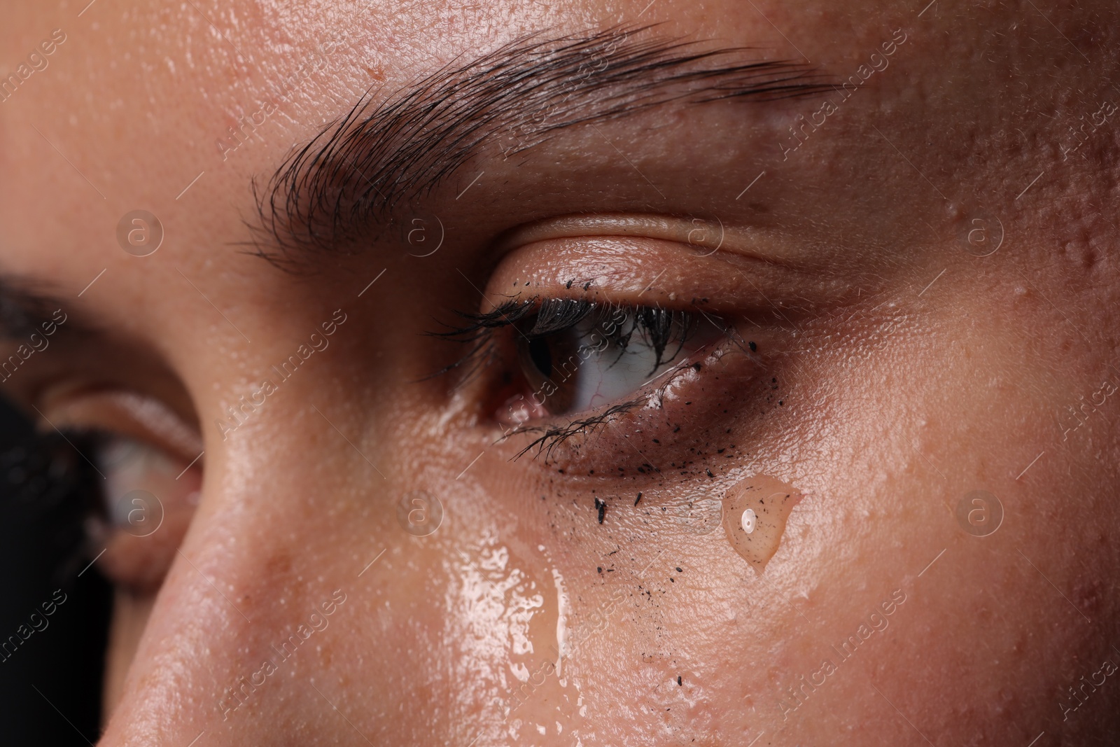 Photo of Sad woman crying on black background, closeup